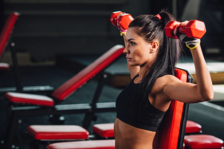 push pull legs split, woman performing a dumbbell shoulder press